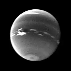 Photo en noir et blanc de Neptune, la Grande Tache sombre est représentée et entourée de nuages très blancs.