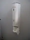 Distributeur vertical de papier toilette, avec déroulement du rouleau dans le sens horaire.