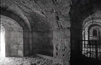 Photographie en noir et blanc d'un passage voûté en maçonnerie de grand appareil.