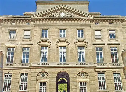 L'Expérience et la Vigilance assises aux côtés d'un cadran surmonté d'un coq (1770), fronton, Paris, hôtel de la Monnaie.