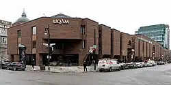 Bâtiment moderne de briques rouges, à deux étages situé à un carrefour.