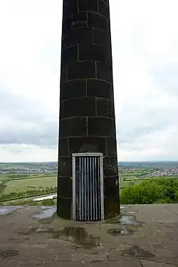 Une porte dans une colonne de pierre, recouverte d'une grille métallique