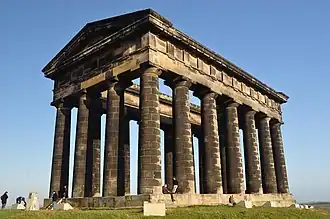 Un monument dans le style d'un temple grec, fait de pierre noircie.