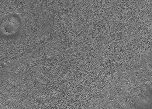 Gros plan sur la surface de Phaethontis. Les cavités visibles pourraient avoir été formées par la sublimation de glace d'eau.