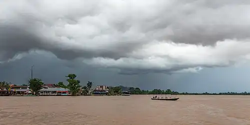 Pirogue sur le Mékong sous de lourds nuages gris pendant la mousson avant une tempête à Don Det.