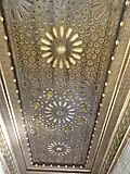 Vue d'un plafond sculpté de rosaces et de motifs géométriques divers.