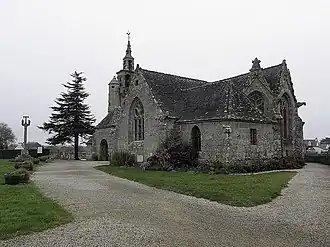 Vue du sud-est. Au-dessus du porche sud, apparaît le haut de la tourelle et du clocher. Puis viennent le croisillon sud et la sacristie, qui cache une partie du chevet.