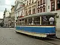 Un tramway ancien crème à bande bleue en circulation.