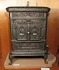 Poêle Alsace-Lorraine, fabriqué à Mertzwiller. Sur les portes sont représentées une Alsacienne en coiffe traditionnelle, ornée d'une cocarde et une Lorraine portant un bonnet lorrain.