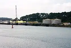 Photo d'un cours d'eau avec des unités circulaires de stockage et du soufre sur la rive