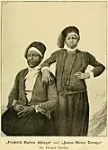 Dessin noir et blanc représentant deux hommes africains habillés d'une chemise et d'une jupe et coiffés d'un fez, l'un assis et l'autre debout le coude posé l'épaule du premier.