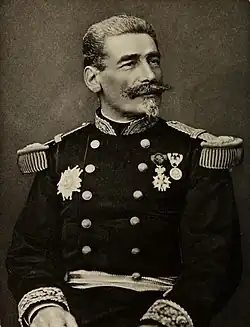 Photo en noir et blanc d'un homme, debout, en tenue de général et portant des décorations.