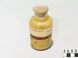 Photographie d'un pot en verre rempli d'un liquide jaunâtre.