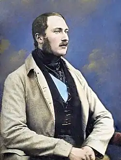 Peinture du buste d'un homme. Il porte une veste grise, un veston noir et la moustache.