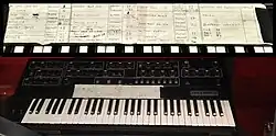 Un piano aux touches blanches et noires au-dessus duquel se trouve une liste de chansons.