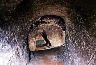 Photographie en couleurs d'une nappe d'eau au bas d'un escalier taillé dans la pierre.