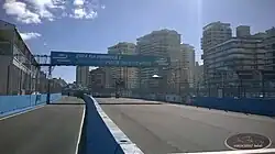 Photographie d'une ligne de départ/arrivée d'un circuit, sous un ciel bleu.