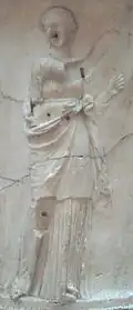 Lachésis sur le Puteal de la Moncloa, tête de puits en marbre de style néo-attique du IIe&nbsp;siècle, Musée archéologique national de Madrid. Elle chante le passé.