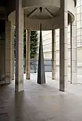Adalberto Mecarelli sculpteur, spécialiste des jeux de lumière a créé une pyramide très élancée, placée sous la rotonde d’entrée de telle sorte que les ombres portées prolongent dans l’espace la signification du volume.
