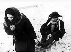 Une femme âgée traîne un homme souffrant de la faim pendant le siège de Léningrad, 7 février 1942.
