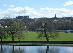 Photographie en couleurs d'un stade devant un fond urbain.