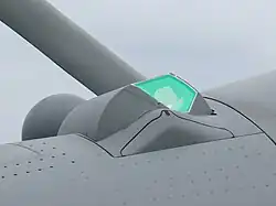 Vue en gros plan de profil du capteur TV/IR de l'OSF, protégé par un hublot aérodynamique qui apparait vert. La carlingue de l'avion est grise.