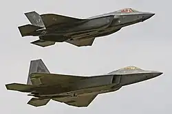 Photo de deux avions de chasse en vol, l'un étant au-dessus de l'autre. Ils ont tout les deux des formes et tailles similaires, mais pas identiques.