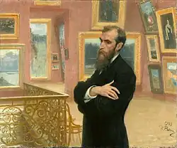 Portrait d'un homme de trois quart, des tableaux accrochés aux murs.