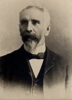 Photographie noir et blanc d'un homme en habit avec nœud papillon.