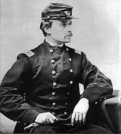 Photographie noir et blanc en buste, assis, d'un homme blanc moustachu en uniforme des armées Nordistes, coude posé sur un siège et l'autre main sur les genoux