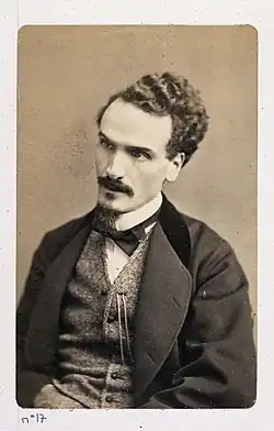 Photographie d'un homme portant bouc et moustache.