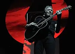 Photo en contre-plongée d'un homme vêtu de noir jouant d'une guitare elle aussi noire
