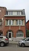 Au no&nbsp;30 : maison Art Déco de deux niveaux symétriques sous mansarde, inscription « G. VANHOVE / ARCH. 1934 » sur le soubassement. Parement à jeu de briques rouges couchées et dressées, à joints horizontaux accentués.