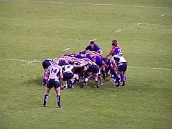 Photographie d'une mêlée dans un match de rugby à XV, entre l'équipe d'Écosse en blanc et l'équipe de Roumanie en bleu