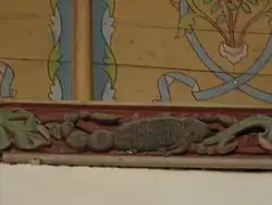 Photographie d'une poutre sculptée et peinte représentant un scorpion