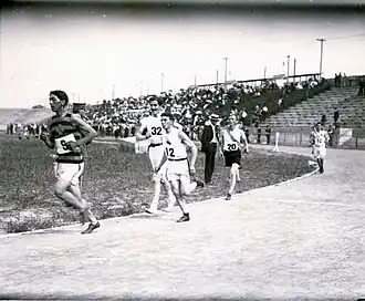 Cinq hommes sont visibles en train de faire des tours d'une piste d'athlétisme.