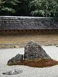 Le mur d'argile, qui est souillé par l'âge avec des tons brun et orange subtils, reflète wabi, le jardin de pierres sabi.