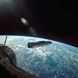 Photographie couleur du vaisseau spatial Agena dans l'espace avec la Terre en arrière-plan.