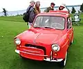Une voiture rouge vue de l'avant gauche sur de l'herbe.