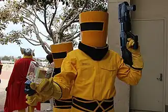 Cosplay d'agents de l'AIM, dont celui au premier plan tient le Cube cosmique.