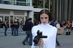 Femme portant une robe blanche et un pistolet.
