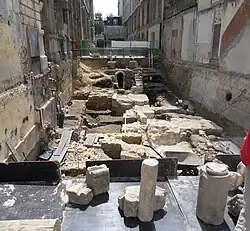 Vue générale du chantier de fouilles en juin 2013. Niveaux successifs : zone romaine, terre agricole du cloître avec une pierre tombale encore en place, début du chœur, extrémité de la nef, au fond : égout haussmannien (1860).