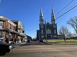 Coin des rues Notre-Dame et Saint-Paul, commerces, résidences privées et église catholique.