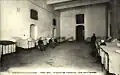 Photo en noir et blanc d'une salle bordée de lits avec des femmes  assises