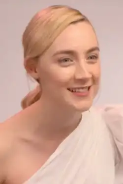 Photo d'une femme blonde souriante habillée en blanc.