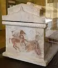 Vue d'un côté du sarcophage avec le côté de la base pourvue de fresques et un toit à double pente