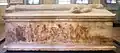 Vue d'un long côté du sarcophage avec sur la partie inférieure une peinture avec des personnages