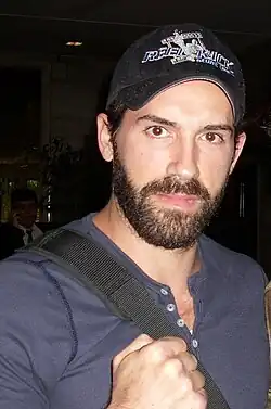 portrait, casquette noire marquée « LA », moustache, barbiche, blouson de cuir