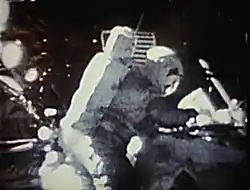 Image prise sur la Lune montrant un astronaute qui oblitère une enveloppe (en raison de la mauvaise qualité, l'enveloppe n'est pas visible).