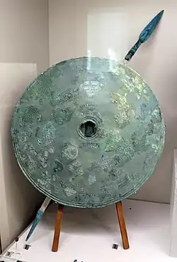 Bouclier rond décoré de bandes concentriques en relief avec des chevaux et des cercles, bronze, nécropole des quatre fontaines, tombe-puits AA1, 750 av. J.-C.